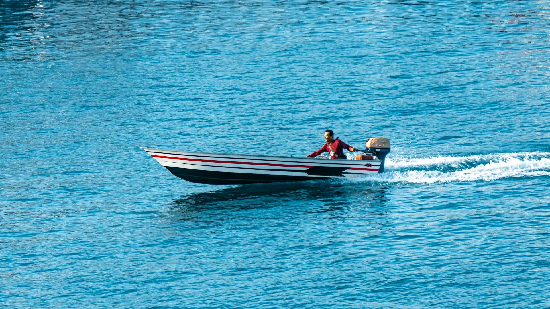 Man driving a small motorboat on blue water